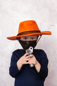 Child cowboy with a gun. Selective focus on pistol barrel.