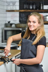 Fototapeta na wymiar Young barista girl makes coffee and smiles. Small business and work concept for young people