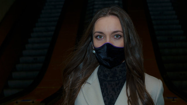 Woman with medical face mask near the escalator in underground. Woman wearing a protective mask against coronavirus. Facial hygienic mask for safety outdoor.