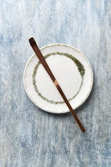 Chashaku Matcha spoon and empty ceramics plate on rustic wooden background. Symbolic image. Asian culture. Top view. Copy space. 