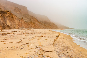 Foggy sea coast with footprints on the sand.