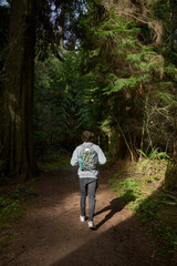 Teenager walking on the forest with a backpack and a water bottle