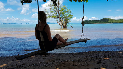 Joven mujer desconocida disfruta de las vistas del mar sentada en una madera.