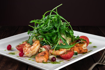 king prawn salad with tomatoes, arugula and grapefruit on a wooden table in a restaurant, close-up. Food for real gourmets