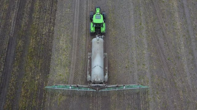 Traktor zieht Güllefass, bringt Gülle auf Acker aus, Vogelperspektive 
