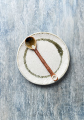 Empty ceramics plate and spoon on rustic wooden background. Top view. Copy space.