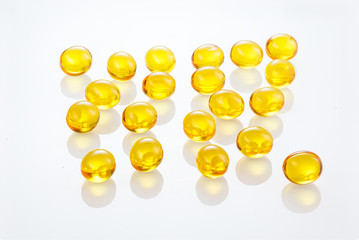 Yellow gel capsules pills. Capsules with yellow medicine on isolated white background. A lot of capsules vitamin D close-up . Bright oil yellow pills. Full depth of field.