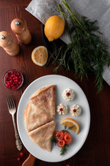 pancakes with red fish, lemon and cranberries on a white plate, table served in restaurant in rustic style, concept of russian festival meal maslenitsa or shrovetide. Top view