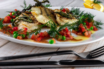 Delicious fillet of zander, rosemary, thyme, lemon and vegetables on a plate in a restaurant close-up. Food for real gourmets