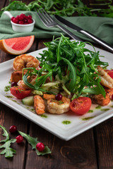 king prawn salad with tomatoes, arugula and grapefruit on a wooden table in a restaurant close-up