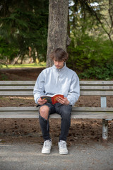 Teenager reading a book in a park.