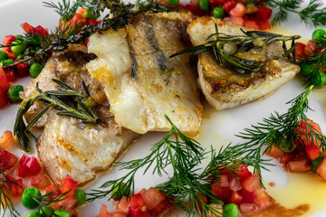 Fillet of zander, rosemary, thyme, lemon and vegetables on a plate in a restaurant close-up