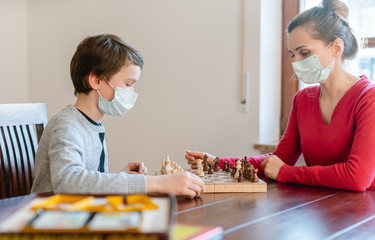 Fototapeta premium Mother and kid during coronavirus crisis playing chess at home