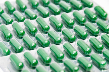 Fototapeta premium Rows of green medicine pills in blisters.