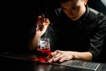close-up barman gently sprinkles on glass with red cocktail and ice