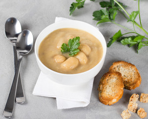 Bean soup-puree with meatballs, parsley and croutons in a bowl on a light background