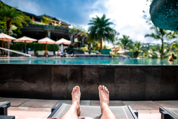 man lying on deck chair near luxury swimming pool
