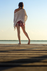 Unrecognizable woman standing on a wooden dock at the sea
