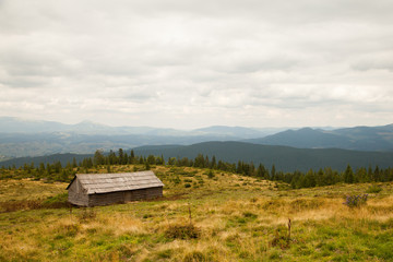 A wooden house in the background of the Carpathian mountains. Mountain landscape in Ukraine. Panorama of the mountains. A lenticular mountain landscape.