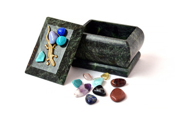 Malachite box and a scattering of multi-colored stones on a white background