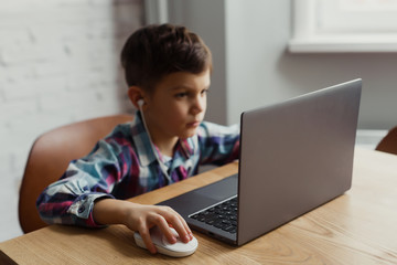 child sitting at a table looking at a laptop, self-study, online training, education at home