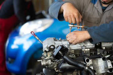 An auto mechanic repairs an internal combustion engine
