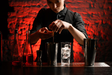 female bartender holding broken egg in her hands over steel shaker.