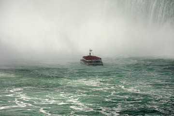 Naklejka premium Into the mist Hornblower tour boat Niagara Falls. Waterfalls at the border of US state of New York and Canadian province of Ontario. Drains Lake Erie into Lake Ontario.