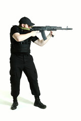 a man in a black military uniform holds machine gun and standing full height on white background