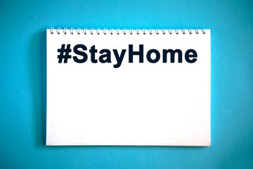 Hashtag STAYHOME text on a notepad on a blue background