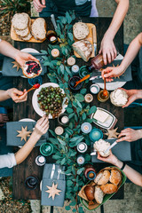 Top view over a dining table, decorated with eucalyptus leaves, with tableware and food. Backyard picnic with friends or neighbors.   