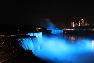 Niagara Falls dark night soft blue lights view to Canada. Waterfalls at the border of US state of New York and Canadian province of Ontario. Drains Lake Erie into Lake Ontario.