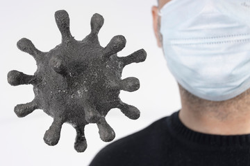 Gray particle of coronavirus on the background of a man in a medical mask