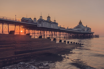 Fototapeta premium Eastbourne Pier at sunrise with a groyne in the foreground 