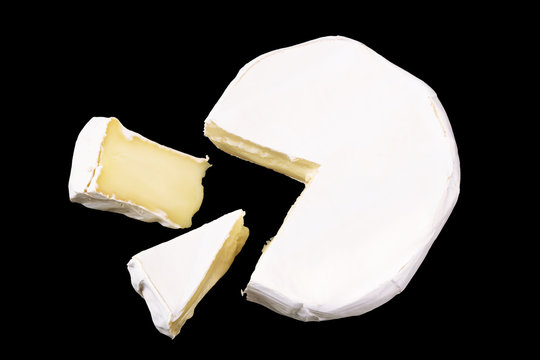 Camembert With Slices Isolated On Black Background. Soft Cheese Covered With Edible White Mold View From Above. Top View