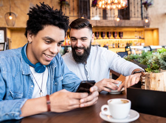 Men looking at the phone and smiling in the cafe with some coffee.