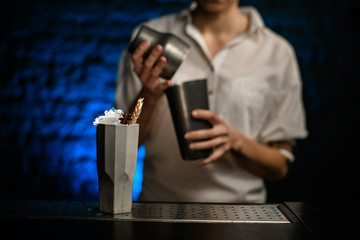 Ceramic glass with ice decorated with plants stands on bar counter.