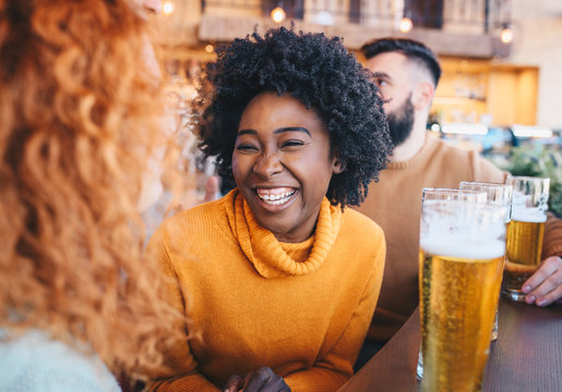 Two Friends Talking To Eachother And Smiling In The Cafe.