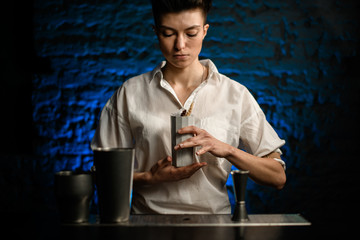 bartender holds ceramic glass with cocktail and looks at it.