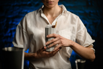 Close-up bartender holds ceramic glass with cocktail