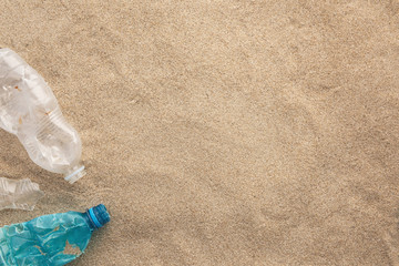 Ecological disaster and pollution of the world ocean. Used plastic spilled on the sand, top view