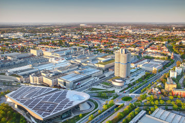 Modern European aerial cityscape with skyscraper, industrial, commercial and residential buildings and circle intersection of roads at sunset in outskirts of Munchen Bavaria Germany Europe