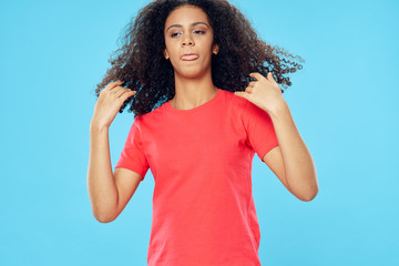 Fototapeta premium Girl in a red T-shirt on a blue background curly hair