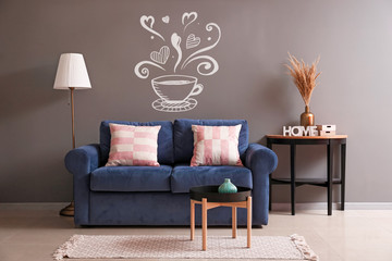 Interior of modern room with comfortable sofa near wall with drawn cup of coffee