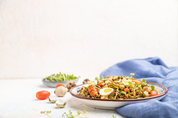 Mung bean porridge with quail eggs, tomatoes and microgreen sprouts on a white concrete background. Side view, selective focus, copy space.