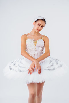 Attractive young ballerina with a beautiful body in leotard dancing tiptoes in photostudio isolated on white background. Showing the beauty of such classical art as ballet.