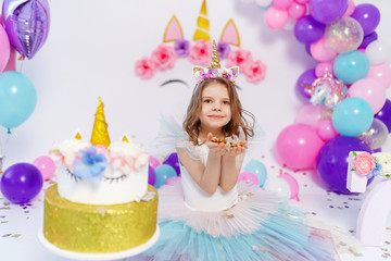 Obraz na płótnie Canvas Unicorn Girl throws confetti. Idea for decorating unicorn style birthday party. Unicorn decoration for festival party girl.