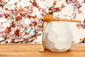 Jar with sweet honey on table in beautiful garden on spring day