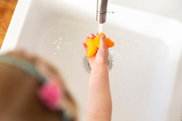 A little girl washing her hands with an orange butterfly soap