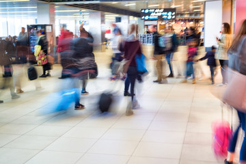 Airport interior people walking in motion blur with their luggage